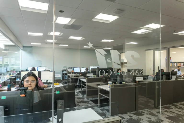 Photo of a modern office seen through a glass wall with a large “211 SAN DIEGO” logo