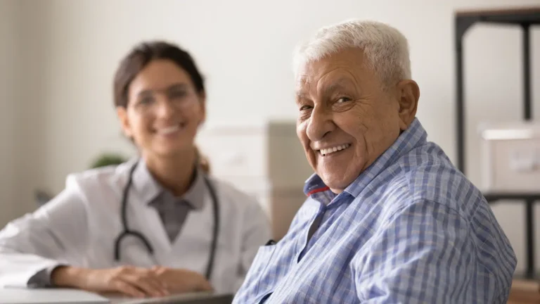 Smiling older man seated during a medical consultation with a doctor in the background